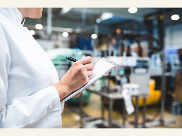 Person recording inspection notes in a production area