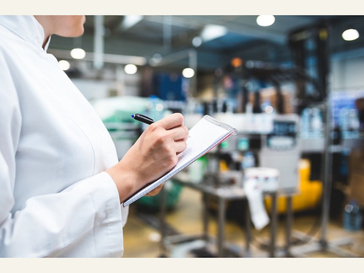 Person recording inspection notes in a production area